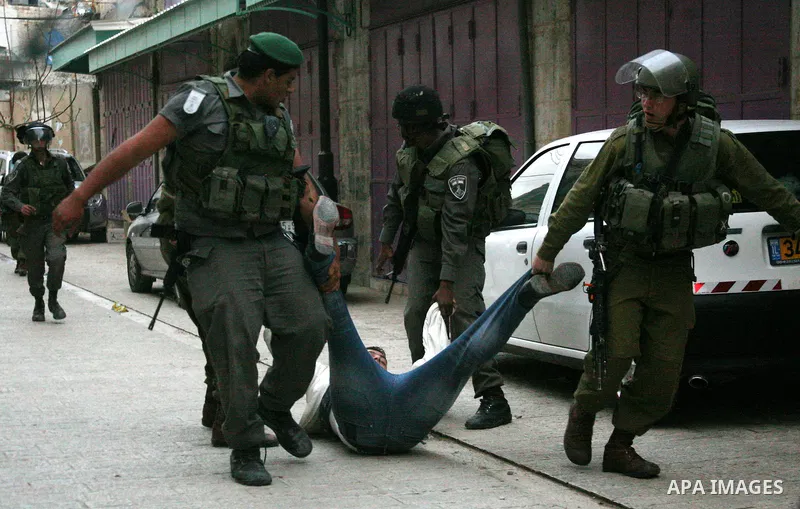 Israeli policemen and soldiers detain Palestinian protesters and foreign activists on April 01, 2012, after they took refuge in an abandoned house and fly a Palestinian flag on the rooftop of the building near the Beit R...