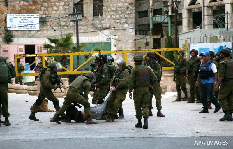 Israeli policemen and soldiers detain Palestinian protesters and foreign activists on April 01, 2012, after they took refuge in an abandoned house and fly a Palestinian flag on the rooftop of the building near the Beit R...
