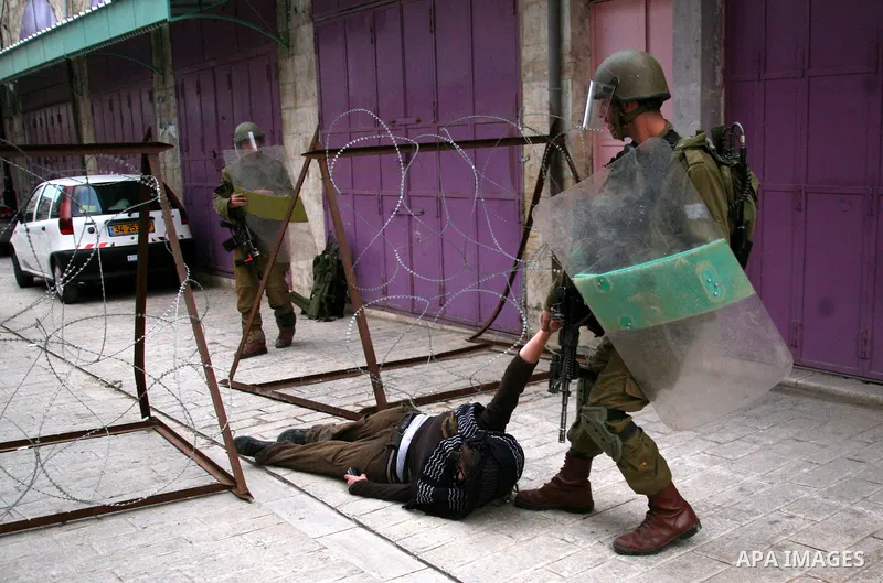 Israeli policemen and soldiers detain Palestinian protesters and foreign activists on April 01, 2012, after they took refuge in an abandoned house and fly a Palestinian flag on the rooftop of the building near the Beit R...