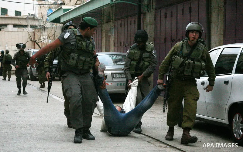 Israeli policemen and soldiers detain Palestinian protesters and foreign activists on April 01, 2012, after they took refuge in an abandoned house and fly a Palestinian flag on the rooftop of the building near the Beit R...