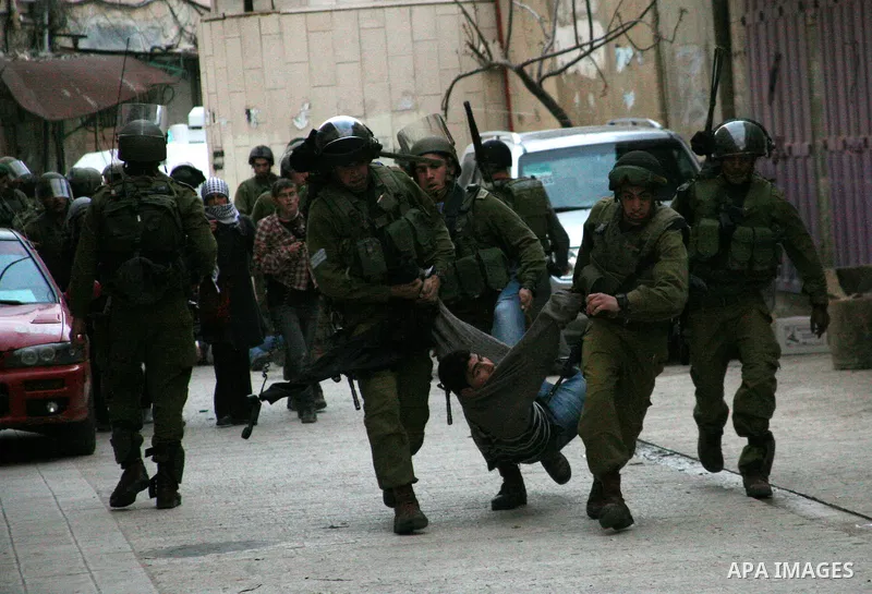 Israeli policemen and soldiers detain Palestinian protesters and foreign activists on April 01, 2012, after they took refuge in an abandoned house and fly a Palestinian flag on the rooftop of the building near the Beit R...