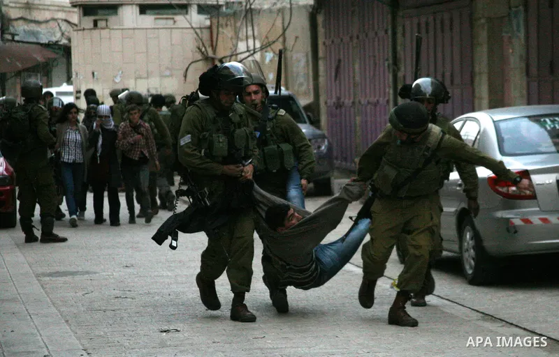 Israeli policemen and soldiers detain Palestinian protesters and foreign activists on April 01, 2012, after they took refuge in an abandoned house and fly a Palestinian flag on the rooftop of the building near the Beit R...