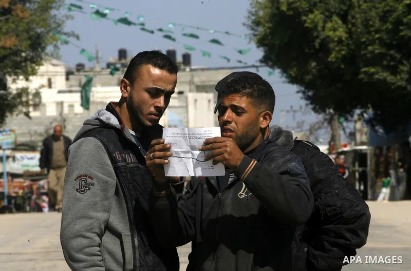 Palestinians read sheets which were thrown by Israeli aeroplane warning the Palestinians from reaching the no-go zone on the border with Israel,in the Rafah on the southern Gaza Strip on April 2,2012. Photo by Eyad Al Ba...