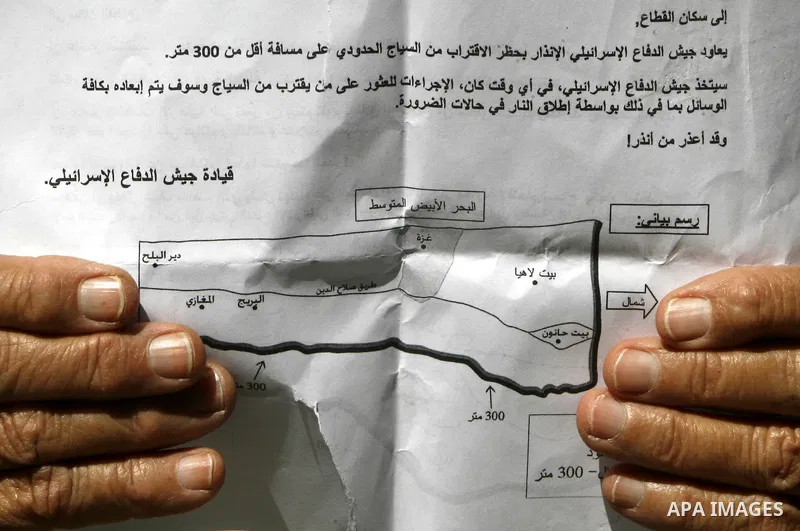 Palestinians read sheets which were thrown by Israeli aeroplane warning the Palestinians from reaching the no-go zone on the border with Israel,in the Rafah on the southern Gaza Strip on April 2,2012. Photo by Eyad Al Ba...
