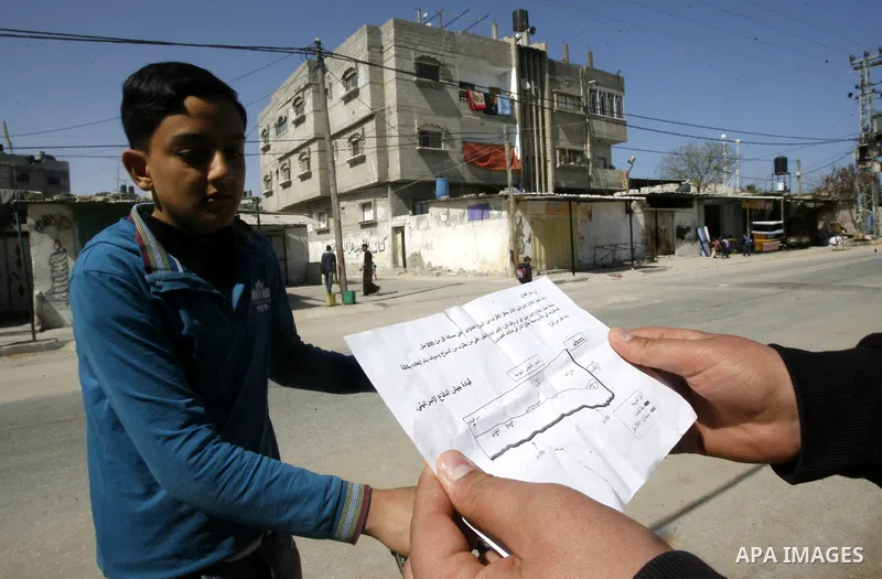 Palestinians read sheets which were thrown by Israeli aeroplane warning the Palestinians from reaching the no-go zone on the border with Israel,in the Rafah on the southern Gaza Strip on April 2,2012. Photo by Eyad Al Ba...