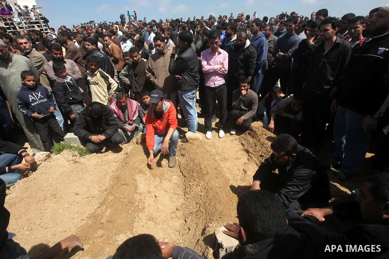 Palestinians mourn at a cemetery during the funeral of three children who died in a domestic fire during their funeral in Deir al-Balah in the central Gaza Strip on April 02, 2012. The three Palestinian children, aged tw...