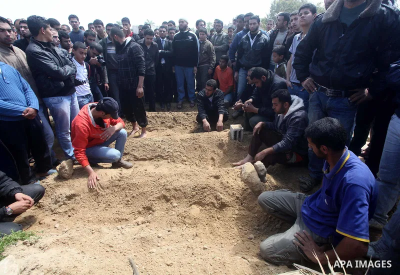 Palestinians mourn at a cemetery during the funeral of three children who died in a domestic fire during their funeral in Deir al-Balah in the central Gaza Strip on April 02, 2012. The three Palestinian children, aged tw...