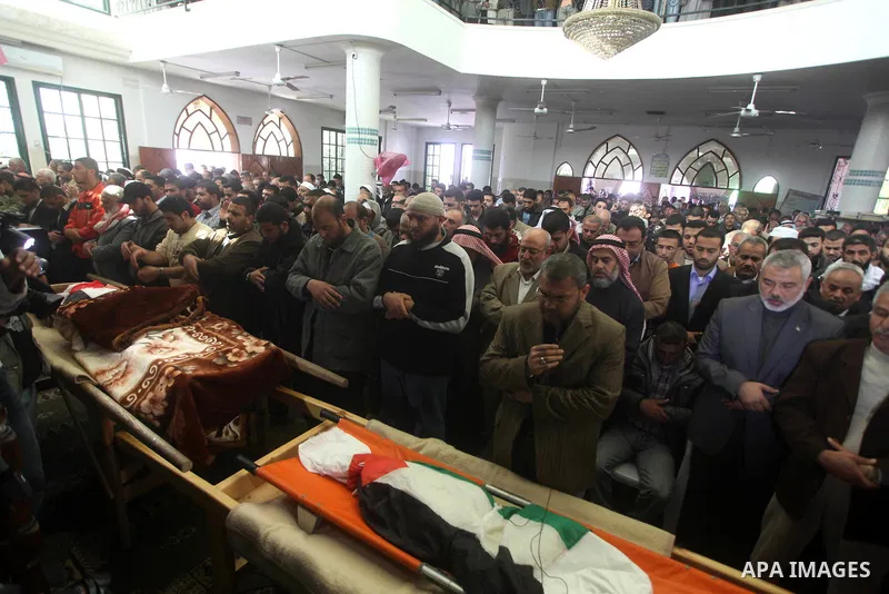 Palestinian mourners pray at the bodies of three children who died the previous day in a domestic fire during their funeral in Deir al-Balah in the central Gaza Strip on April 02, 2012. The three Palestinian children, ag...