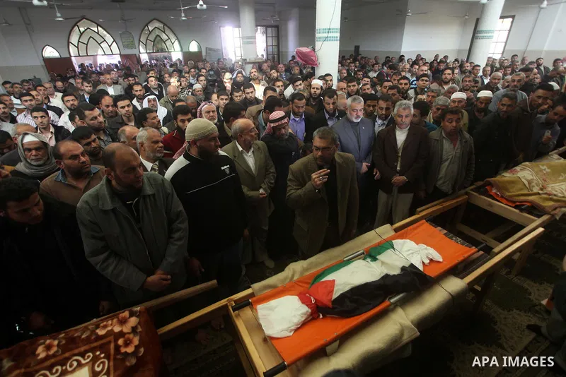 Palestinian mourners pray at the bodies of three children who died the previous day in a domestic fire during their funeral in Deir al-Balah in the central Gaza Strip on April 02, 2012. The three Palestinian children, ag...