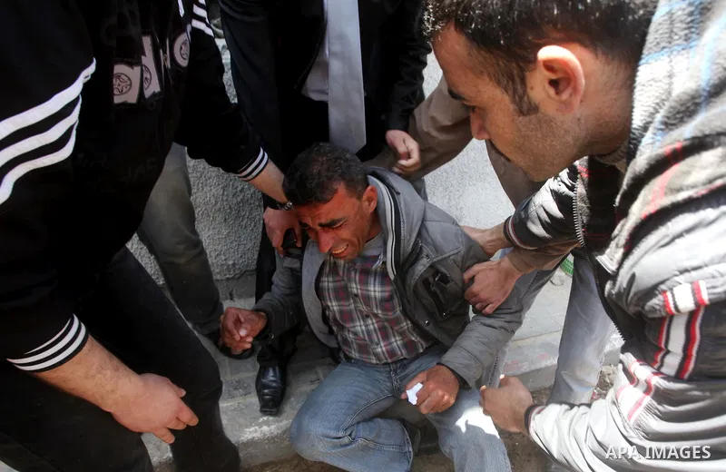 The father (C) of three Palestinian children who were killed the previous day in a domestic fire mourns during their funeral procession in Deir al-Balah in the central Gaza Strip on April 02, 2012. The three Palestinian...
