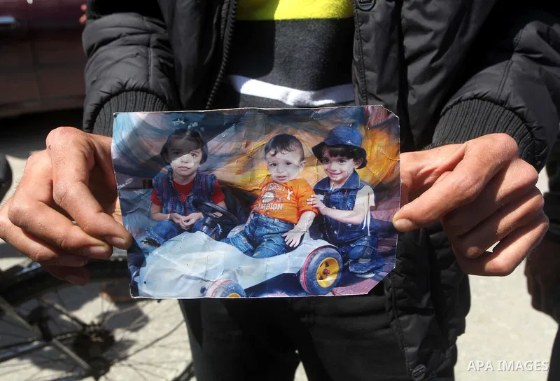 Palestinian mourners hold the pictures of three children (from L-R: Nadine, Sabri and Farah Bashir) who were killed the previous day in a domestic fire during their funeral procession in Deir al-Balah in the central Gaza...