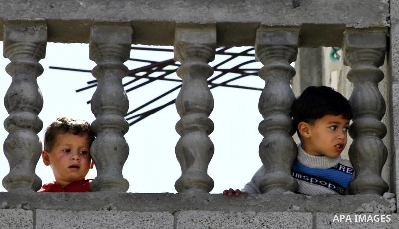 Palestinian relatives look as mourners carry the bodies of three children who died in a domestic fire during their funeral during their funeral procession in Deir al-Balah in the central Gaza Strip on April 02, 2012. The...