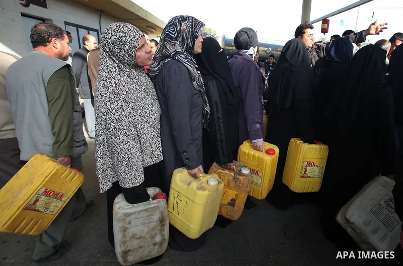 Palestinians wait in a queue to fill containers with fuel at a petrol station in Gaza City on April 2, 2012. The International Committee of the Red Cross (ICRC) began transferring emergency supplies of fuel to the Gaza S...