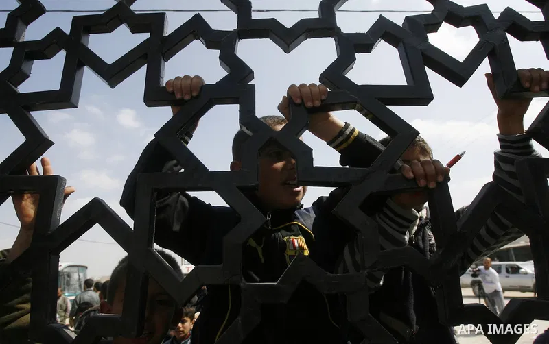 Palestinian boys climb a fence during a rally near Rafah border crossing between Egypt and the southern Gaza Strip, calling on the Egyptian authorities to supply the Gaza Strip with fuel and electricity April 3, 2012. Th...