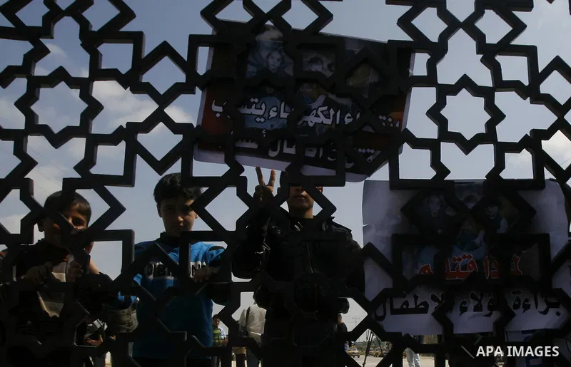 Palestinian boys hold a poster of three children who were killed in a fire caused by a candle being used due to lack of electricity during a protest against the electricity crisis near the southern Gaza Strip's Rafah bor...