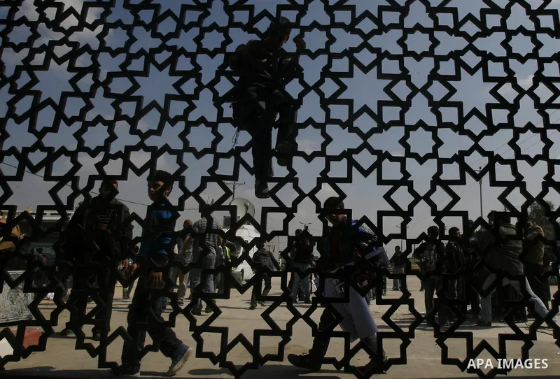 Palestinian boys climb a fence during a rally near Rafah border crossing between Egypt and the southern Gaza Strip, calling on the Egyptian authorities to supply the Gaza Strip with fuel and electricity April 3, 2012. Th...