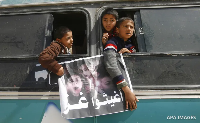 Palestinian boys hold a poster of children reading "Rescue Gaza" as another flashes the victory sign near the southern Gaza Strip's Rafah border crossing with Egypt on April 3, 2012 during a protest against the electrici...
