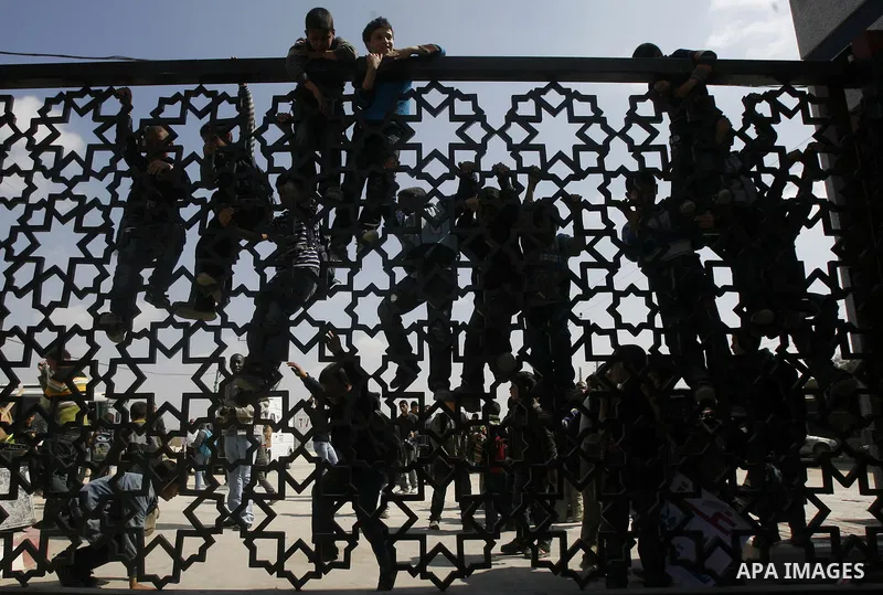 Palestinian boys climb a fence during a rally near Rafah border crossing between Egypt and the southern Gaza Strip, calling on the Egyptian authorities to supply the Gaza Strip with fuel and electricity April 3, 2012. Th...