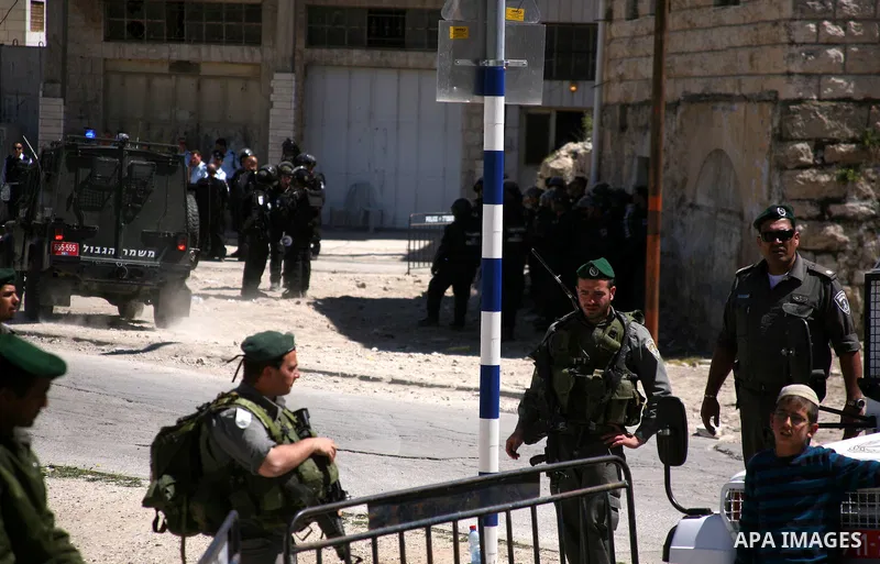 A Jewish settler stands near Israeli border policemen as they prevent her from reaching a building, occupied by Jewish settlers, in the West Bank city of Hebron April 4, 2012. Israeli police evicted Jewish settlers on We...