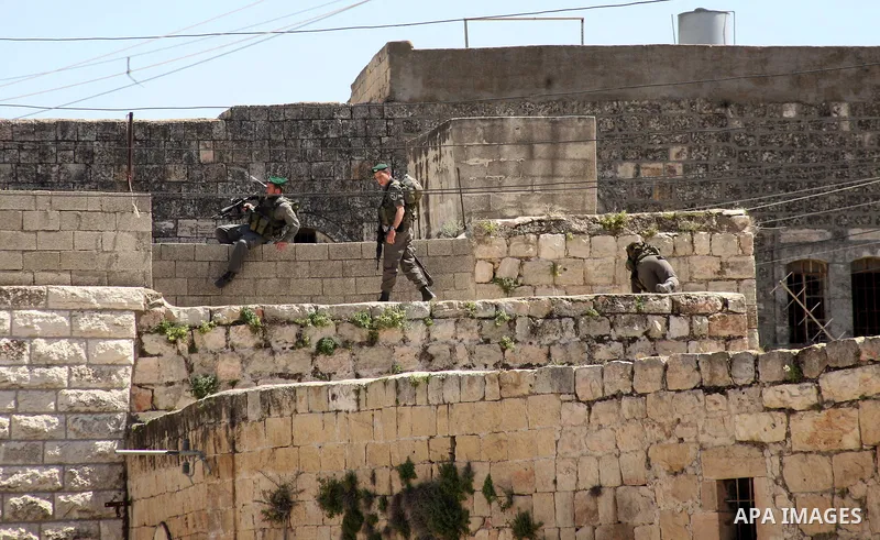 A Jewish settler stands near Israeli border policemen as they prevent her from reaching a building, occupied by Jewish settlers, in the West Bank city of Hebron April 4, 2012. Israeli police evicted Jewish settlers on We...