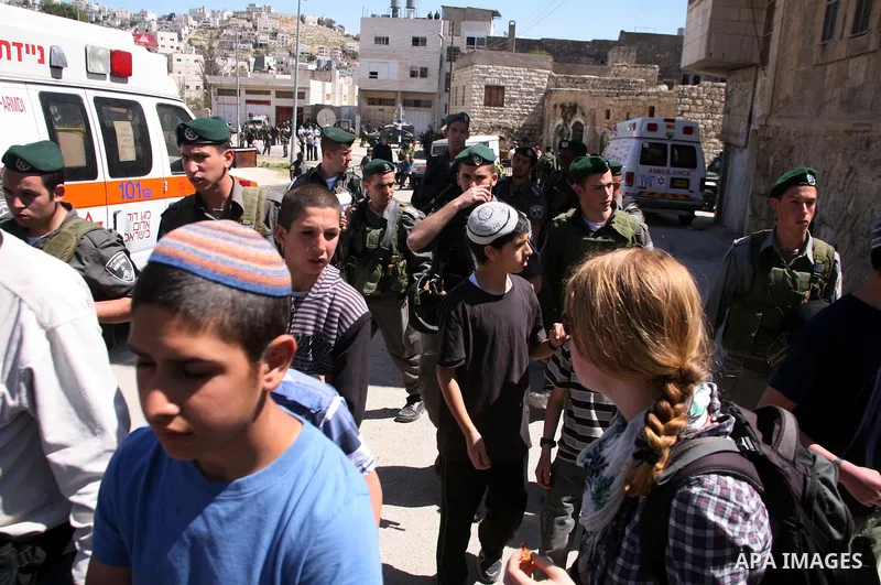 Jewish settlers stands near Israeli border policemen as they prevent her from reaching a building, occupied by Jewish settlers, in the West Bank city of Hebron April 4, 2012. Israeli police evicted Jewish settlers on Wed...