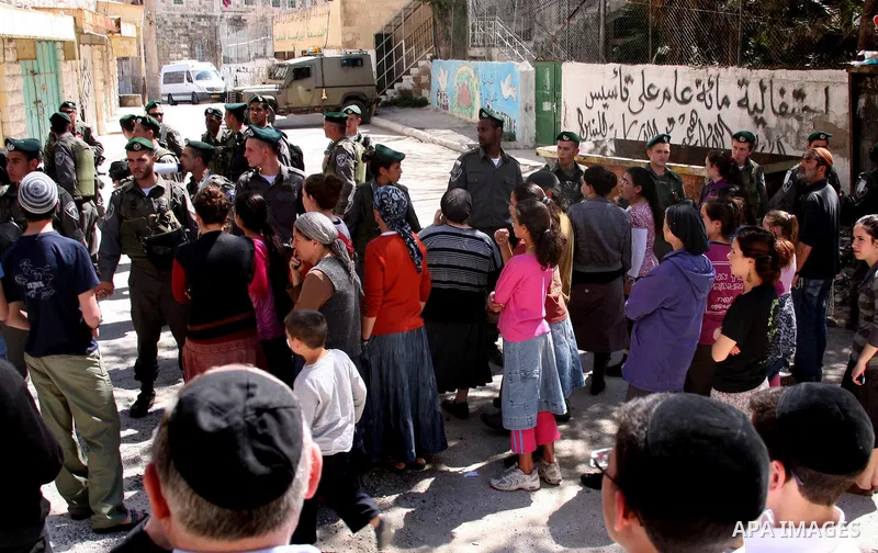 Jewish settlers stands near Israeli border policemen as they prevent her from reaching a building, occupied by Jewish settlers, in the West Bank city of Hebron April 4, 2012. Israeli police evicted Jewish settlers on Wed...