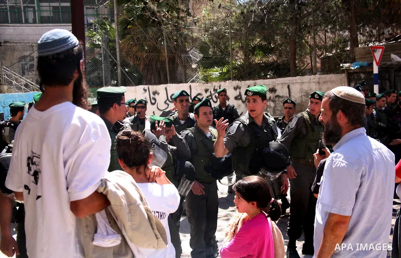 Jewish settlers stands near Israeli border policemen as they prevent her from reaching a building, occupied by Jewish settlers, in the West Bank city of Hebron April 4, 2012. Israeli police evicted Jewish settlers on Wed...