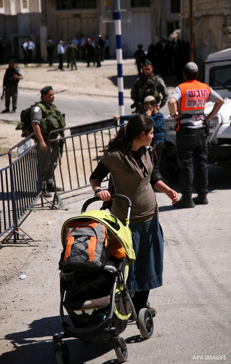 Jewish settlers stands near Israeli border policemen as they prevent her from reaching a building, occupied by Jewish settlers, in the West Bank city of Hebron April 4, 2012. Israeli police evicted Jewish settlers on Wed...