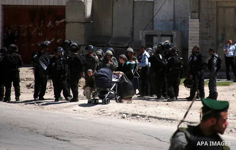 Jewish settlers stands near Israeli border policemen as they prevent her from reaching a building, occupied by Jewish settlers, in the West Bank city of Hebron April 4, 2012. Israeli police evicted Jewish settlers on Wed...