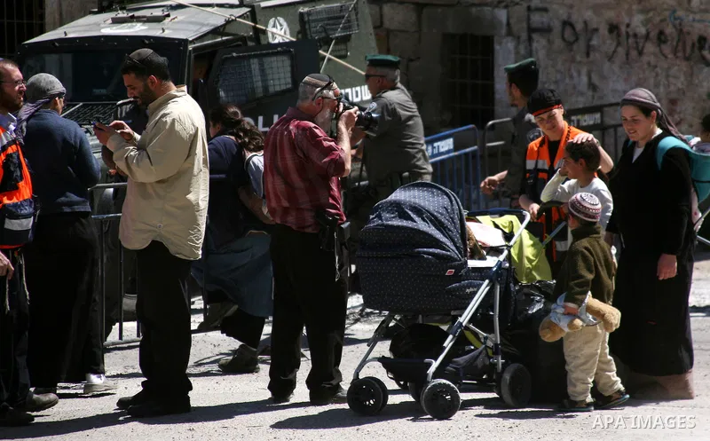 Jewish settlers stands near Israeli border policemen as they prevent her from reaching a building, occupied by Jewish settlers, in the West Bank city of Hebron April 4, 2012. Israeli police evicted Jewish settlers on Wed...