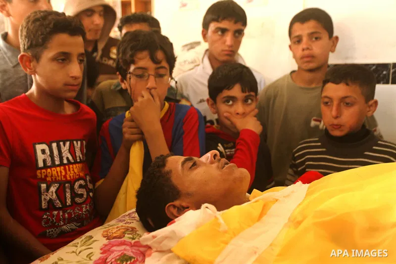 Palestinian children gather around the body of Palestinian youth Hashem Saed, 17-years-old, during his funeral in Gaza City on April 4, 2012, after he was shot overnight close along the border fence between the Gaza Stri...
