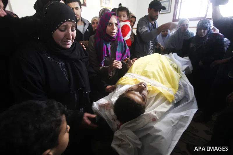Palestinian women grieve as they watch the body of Palestinian youth Hashem Saed, 17-years-old, leave his home during his funeral in Gaza City on April 4, 2012, after he was shot overnight close along the border fence be...
