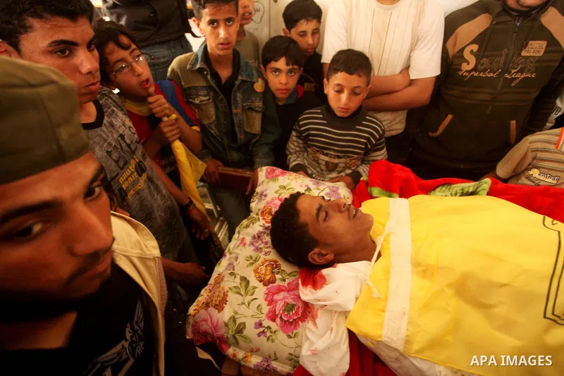 Palestinian children gather around the body of Palestinian youth Hashem Saed, 17-years-old, during his funeral in Gaza City on April 4, 2012, after he was shot overnight close along the border fence between the Gaza Stri...
