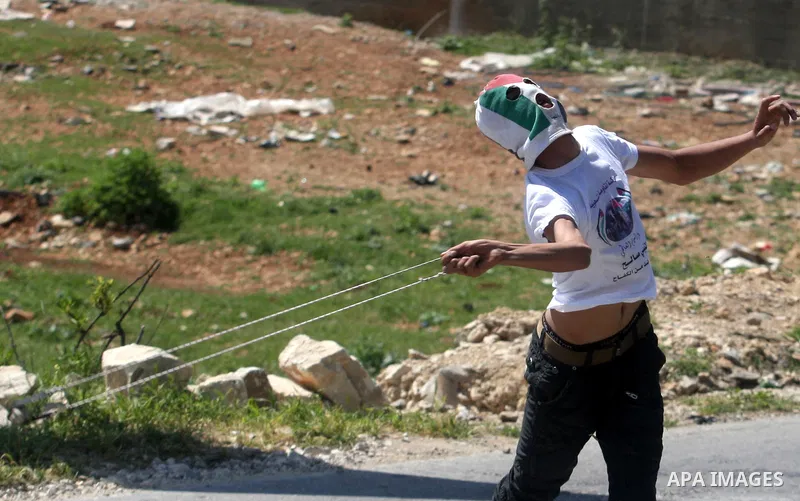 A Palestinian man throws stones towards the Israeli soldiers in the West Bank village of Nabi Saleh, near Ramallah, on April 6, 2012 during a protest against Palestinian land confiscation to expand the Jewish Hallamish s...