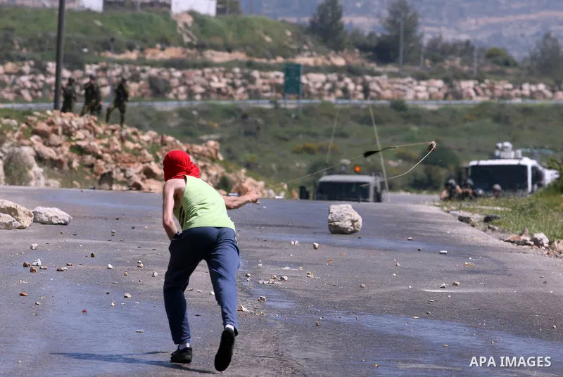 A Palestinian man throws stones towards the Israeli soldiers in the West Bank village of Nabi Saleh, near Ramallah, on April 6, 2012 during a protest against Palestinian land confiscation to expand the Jewish Hallamish s...