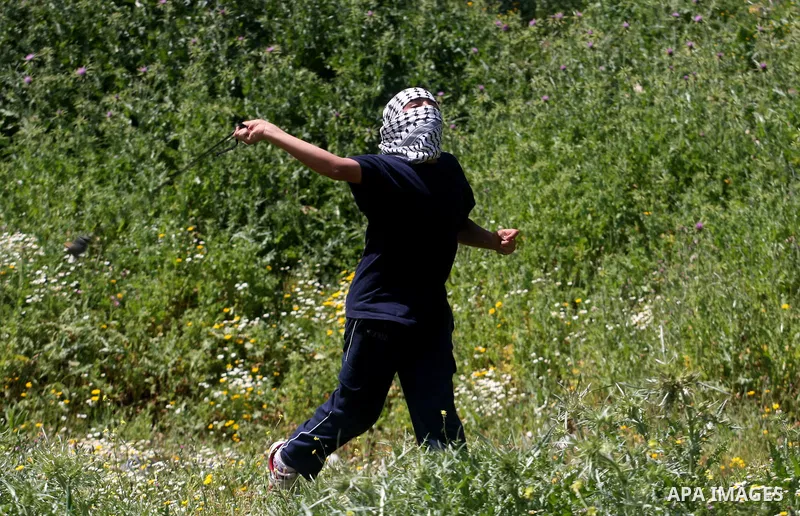 A Palestinian man throws stones towards the Israeli soldiers in the West Bank village of Nabi Saleh, near Ramallah, on April 6, 2012 during a protest against Palestinian land confiscation to expand the Jewish Hallamish s...