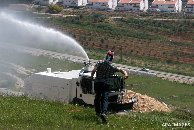 A Palestinian man throws stones towards the Israeli soldiers in the West Bank village of Nabi Saleh, near Ramallah, on April 6, 2012 during a protest against Palestinian land confiscation to expand the Jewish Hallamish s...