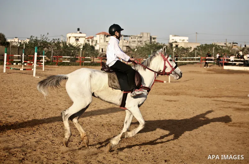 A Palestinian child rides a horse during a championship at Gaza Horse Club in Gaza Strip, 06 April 2012. The clubs is home to some 54 horses and open for the training of male and female children aged between 12 to 23 yea...