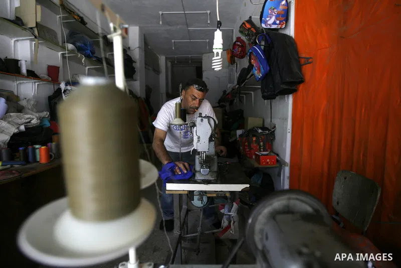 A Palestinian tailor sews of the school bags in his shop in the southern Gaza Strip refugee camp of Rafah, in Apr. 08, 2012. Photo by Eyad Al Baba