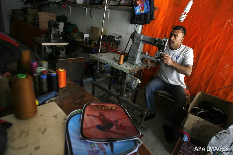 A Palestinian tailor sews of the school bags in his shop in the southern Gaza Strip refugee camp of Rafah, in Apr. 08, 2012. Photo by Eyad Al Baba