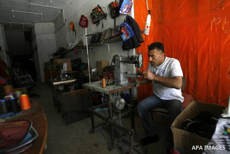A Palestinian tailor sews of the school bags in his shop in the southern Gaza Strip refugee camp of Rafah, in Apr. 08, 2012. Photo by Eyad Al Baba