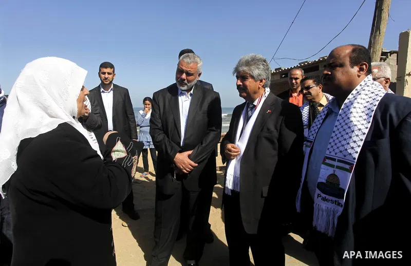 Palestinian Prime Minister in Gaza Strip, Ismail Haniya and the Head of the Bahrani delegation speak with a woman during their tour to al-Shatea refugee camp in Gaza city on April 11,2012. The Bahrani delegation is in an...