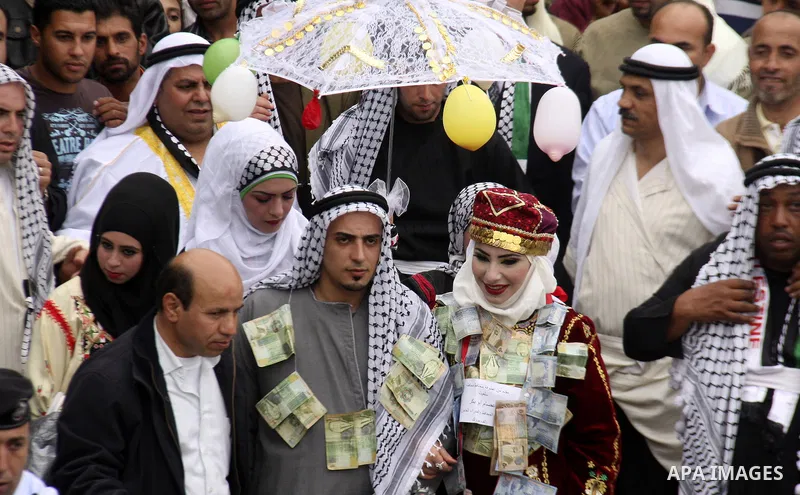 The Palestinian bride and groom Mhaha Salam (R) and Thayer Qasem (L), walk down the street on their wedding day on April 12, 2012 after they traveled from the refugee camp of al-Yarmuk in Syria, to get married in the Wes...