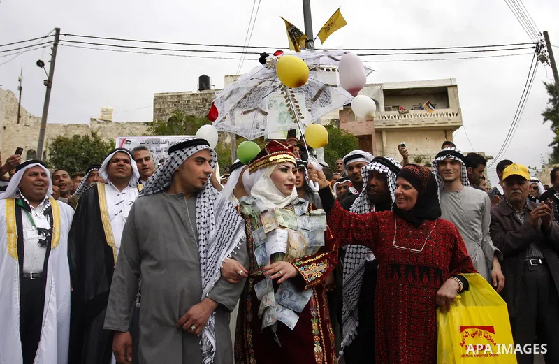 The Palestinian bride and groom Mhaha Salam (R) and Thayer Qasem (L), walk down the street on their wedding day on April 12, 2012 after they traveled from the refugee camp of al-Yarmuk in Syria, to get married in the Wes...