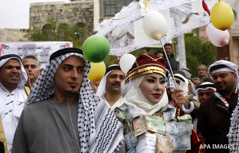 The Palestinian bride and groom Mhaha Salam (R) and Thayer Qasem (L), walk down the street on their wedding day on April 12, 2012 after they traveled from the refugee camp of al-Yarmuk in Syria, to get married in the Wes...