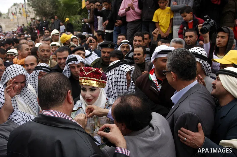 The Palestinian bride and groom Mhaha Salam (R) and Thayer Qasem (L), walk down the street on their wedding day on April 12, 2012 after they traveled from the refugee camp of al-Yarmuk in Syria, to get married in the Wes...
