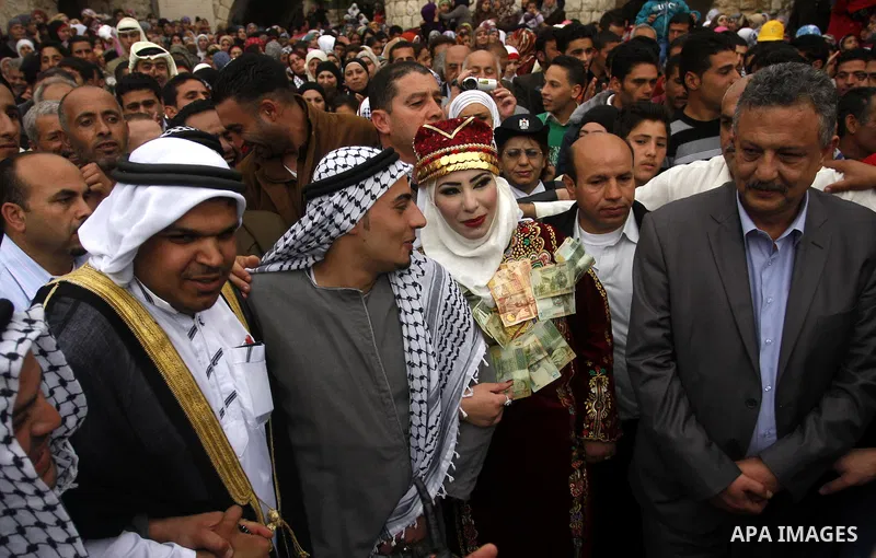 The Palestinian bride and groom Mhaha Salam (R) and Thayer Qasem (L), walk down the street on their wedding day on April 12, 2012 after they traveled from the refugee camp of al-Yarmuk in Syria, to get married in the Wes...