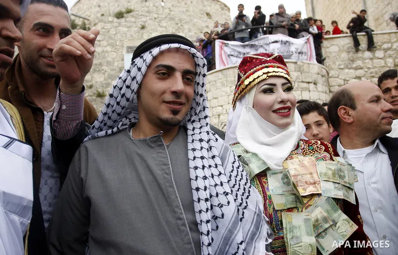 The Palestinian bride and groom Mhaha Salam (R) and Thayer Qasem (L), walk down the street on their wedding day on April 12, 2012 after they traveled from the refugee camp of al-Yarmuk in Syria, to get married in the Wes...