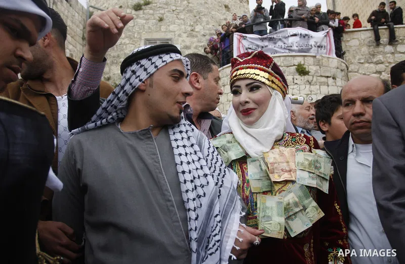 The Palestinian bride and groom Mhaha Salam (R) and Thayer Qasem (L), walk down the street on their wedding day on April 12, 2012 after they traveled from the refugee camp of al-Yarmuk in Syria, to get married in the Wes...