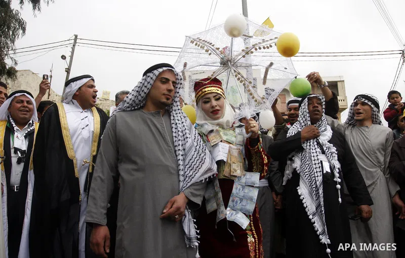 The Palestinian bride and groom Mhaha Salam (R) and Thayer Qasem (L), walk down the street on their wedding day on April 12, 2012 after they traveled from the refugee camp of al-Yarmuk in Syria, to get married in the Wes...